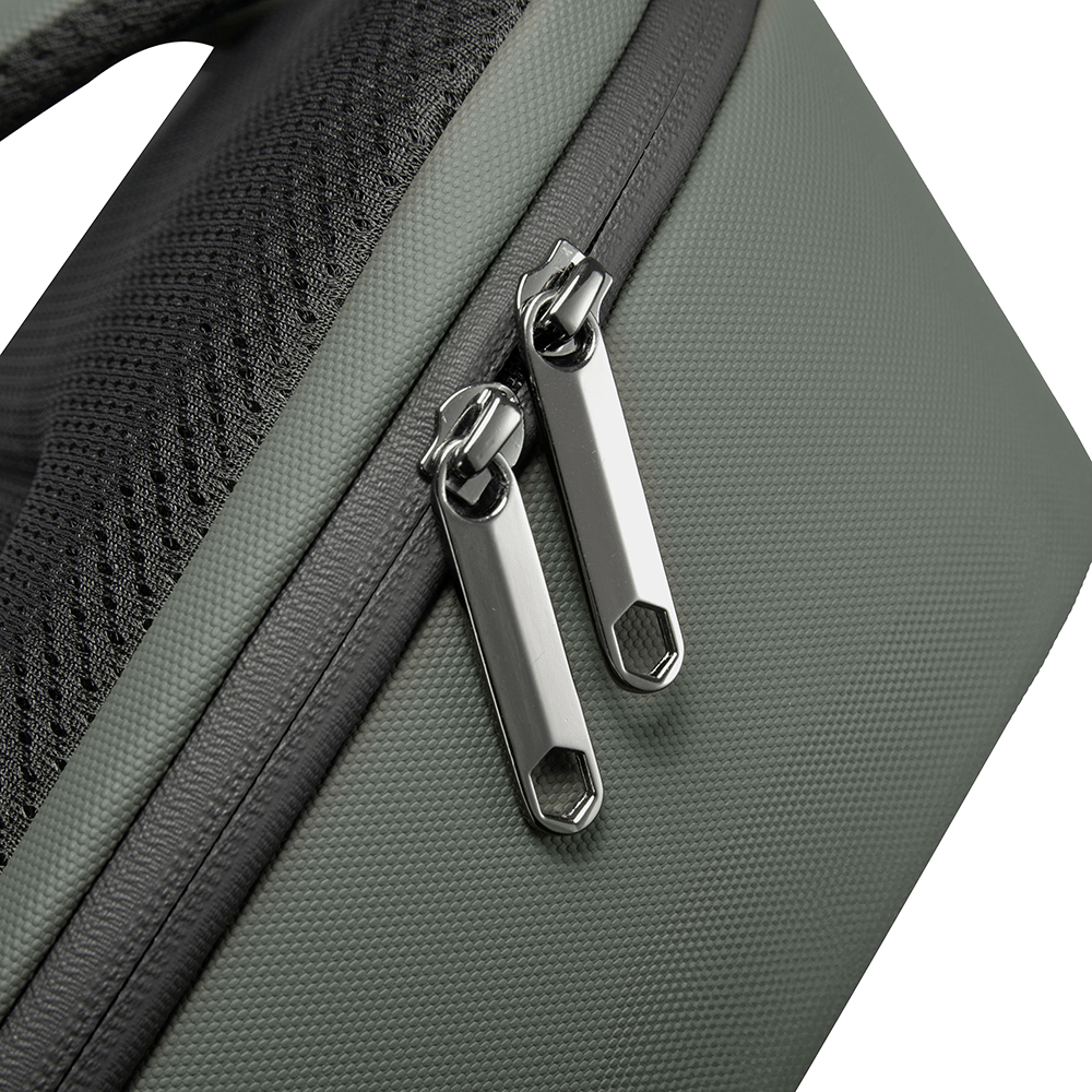 Close-up of double metal zippers on green backpack with textured fabric and padded mesh back panel.